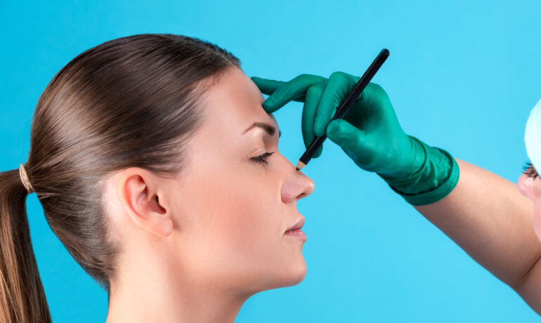 Cosmetic surgeon examining female client in office. Doctor checking woman's face, the eyelid before plastic surgery, blepharoplasty. Surgeon or beautician hands touching woman face.